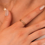 Bague en acier inoxydable couleur or avec dauphins entrelacés, portée sur le doigt d'une femme.