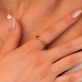 Bague en acier inoxydable couleur or avec dauphins entrelacés, portée sur le doigt d'une femme.