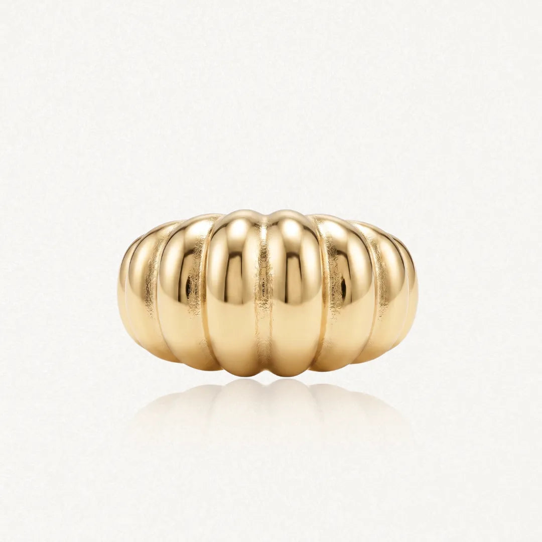 Bague coquillage bombée en acier inoxydable doré, avec reflets, sur fond clair.