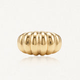 Bague coquillage bombée en acier inoxydable doré, avec reflets, sur fond clair.