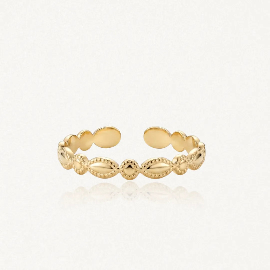 Bague ajustable en acier inoxydable doré, frise de motifs alternés ovales texturés et petits cercles striés.