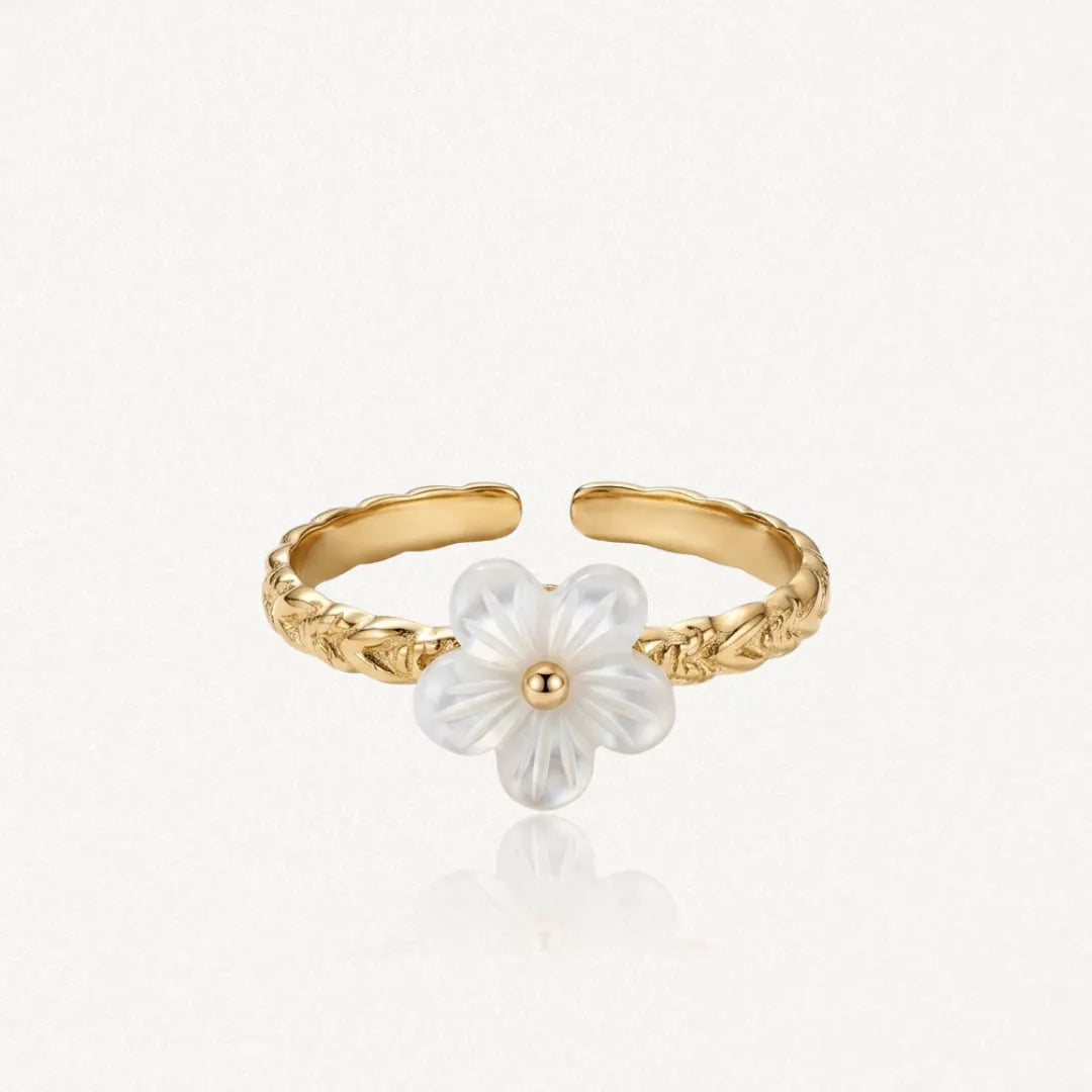 Bague ajustable en acier inoxydable doré à l'anneau gravé, ornée d'une fleur de nacre blanche au cœur doré.