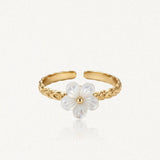 Bague ajustable en acier inoxydable doré à l'anneau gravé, ornée d'une fleur de nacre blanche au cœur doré.