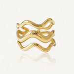 Bague en acier inoxydable doré, composée de trois bandes ondulées lisses et brillantes.