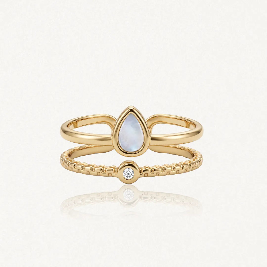 Bague en acier inoxydable doré, composée de deux anneaux. L'un porte une nacre goutte d'eau, l'autre un strass zirconium