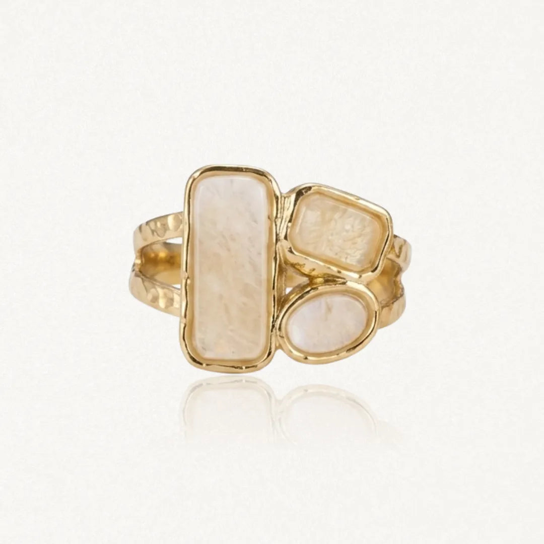 Bague dorée avec trois pierres irrégulières : une rectangulaire, une petite rectangulaire et une ovale, toutes claires et