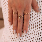Bagues en acier inoxydable doré: design bague corail central, bague branche et bague vague sur une main.