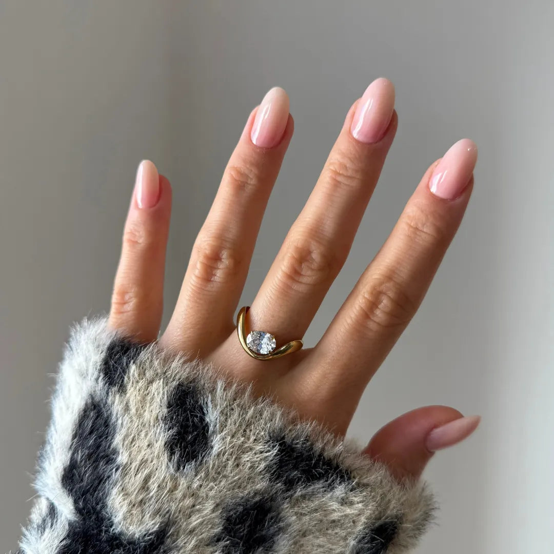 Main avec pull imprimé léopard, portant une bague chevron ouverte en acier inoxydable doré et zirconium rond.