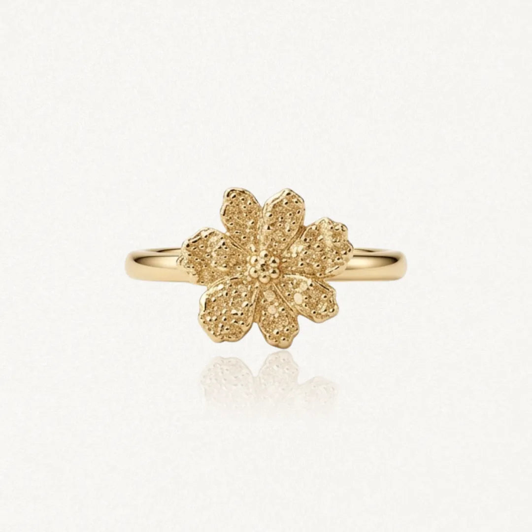 Bague en acier inoxydable doré. Motif de fleur texturée et granuleuse à six pétales, centre détaillé.