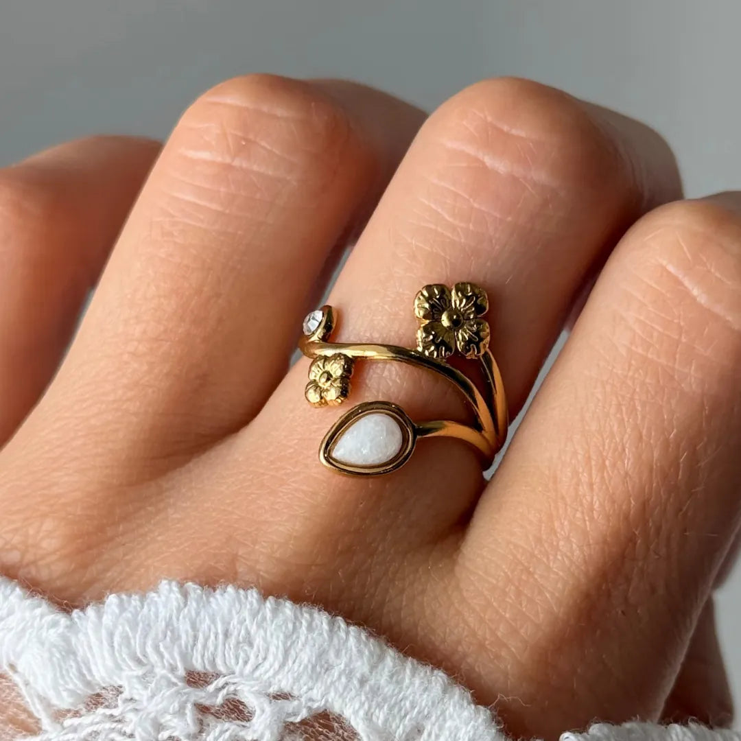 Bague en acier inoxydable dorée, avec motifs floraux, un petit strass et une pierre naturelle de jade blanc en goutte, portée