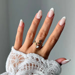 Bague en acier inoxydable doré avec fleur et pierre naturelle de Jade Blanc en forme de goutte. Portée sur une main