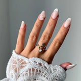 Bague en acier inoxydable doré avec fleur et pierre naturelle de Jade Blanc en forme de goutte. Portée sur une main