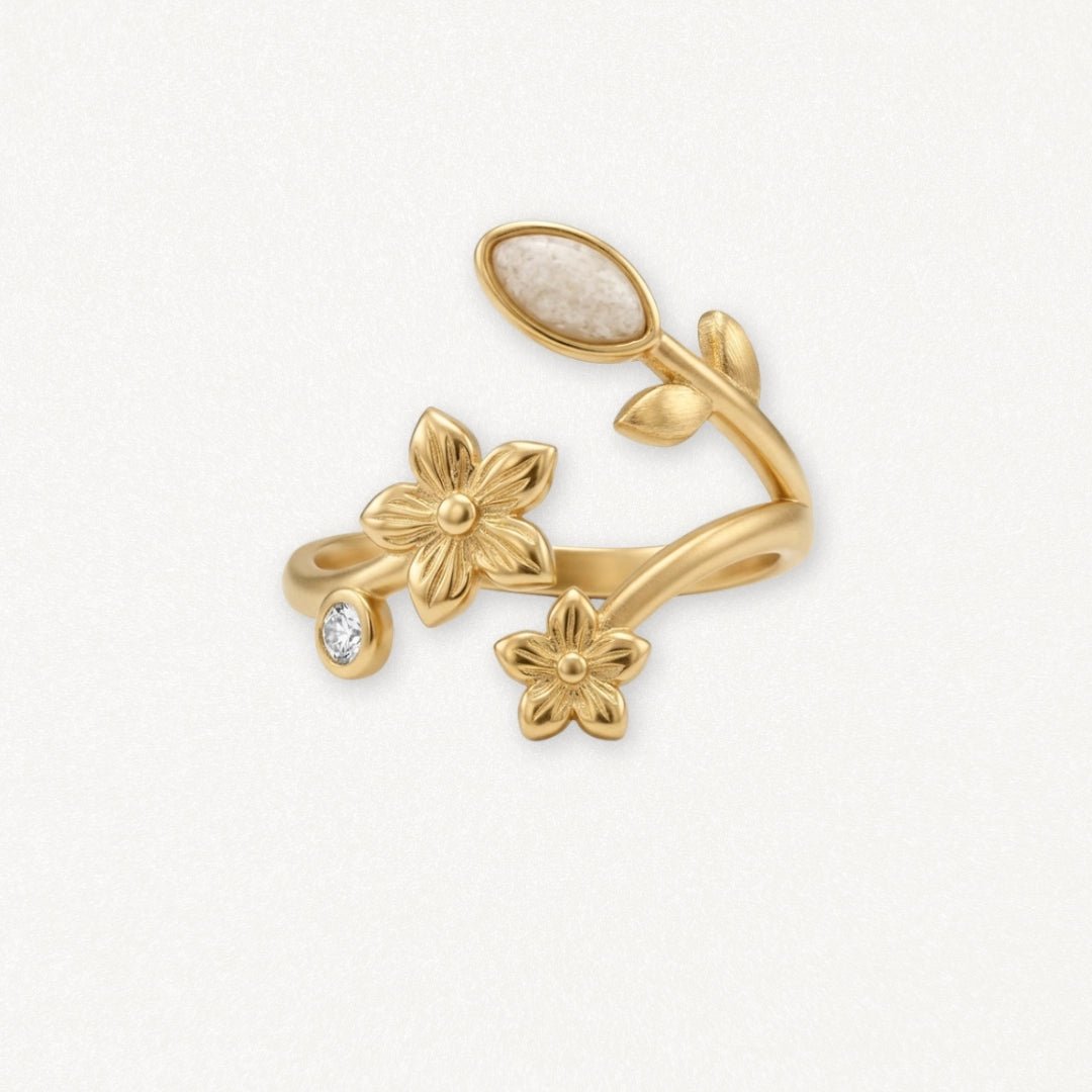 Bague en acier inoxydable doré, design floral élégant avec 2 fleurs, feuilles, pierre ovale blanche et pierre brillante.
