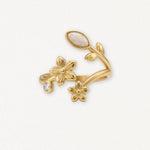 Bague en acier inoxydable doré, design floral élégant avec 2 fleurs, feuilles, pierre ovale blanche et pierre brillante.