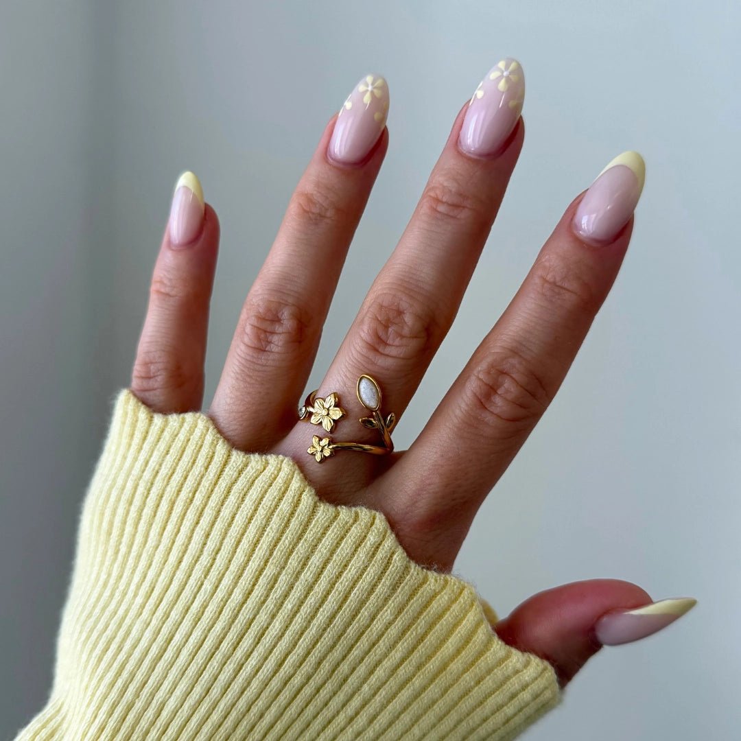 Bague ajustable en acier inoxydable doré, motif floral avec deux petites fleurs et une pierre ovale blanche.