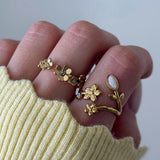 Bagues en acier inoxydable doré, motif floral: grappe de fleurs serties et bague fleur-tige avec pierre blanche ovale.