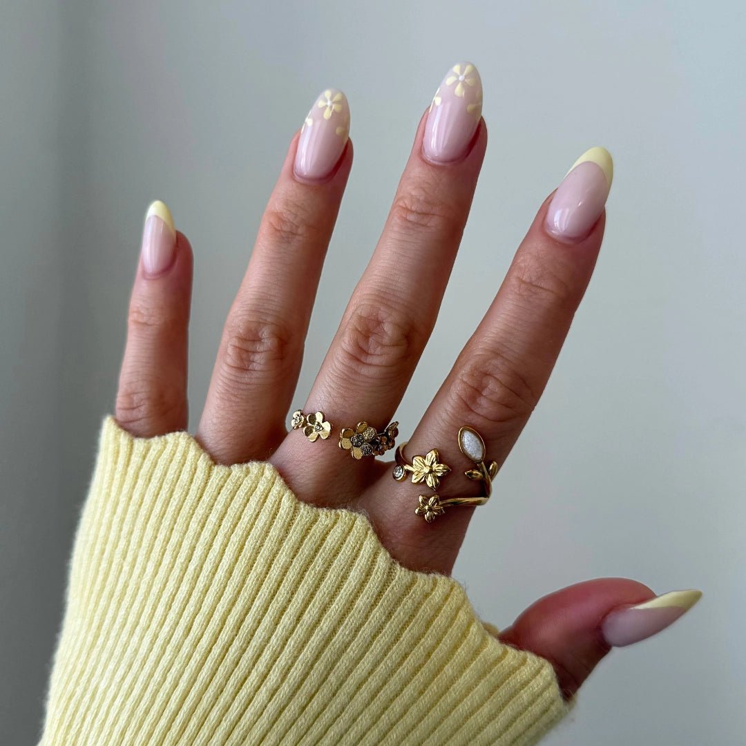 Plusieurs bagues en acier inoxydable doré à motifs floraux et feuilles, dont une bague enveloppante avec pierre ovale, sur