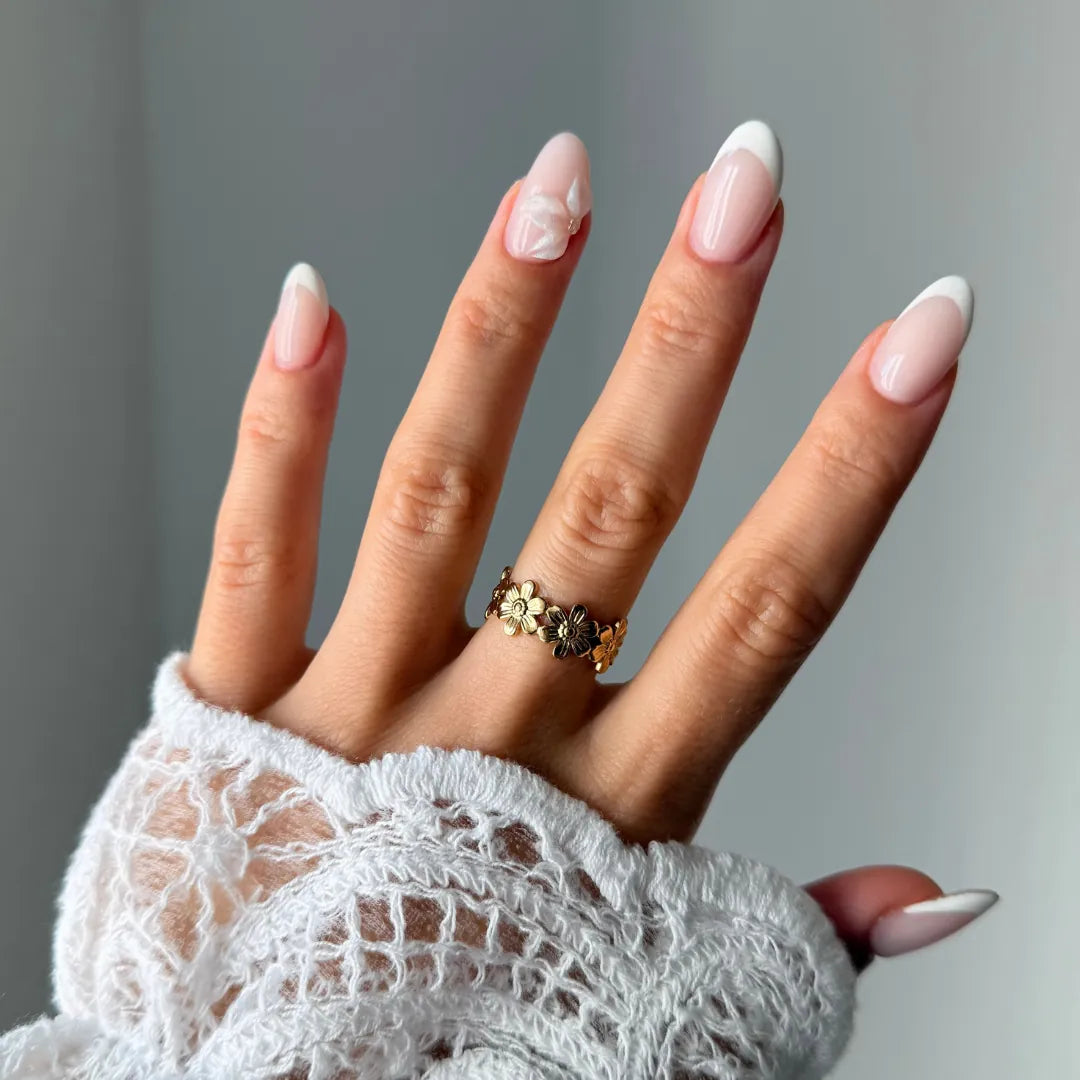 Bague en acier inoxydable dore, ornée d'un bandeau continu de petites fleurs, portée sur une main avec un poignet en