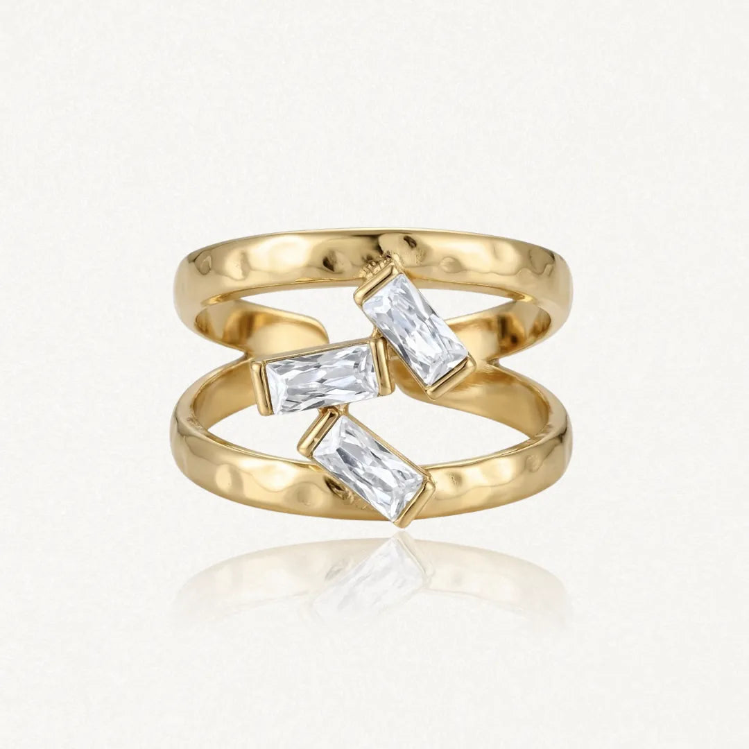 Bague double anneau en acier inoxydable doré martelé, ornée de trois pierres baguette en Zirconium entre les deux bandes.