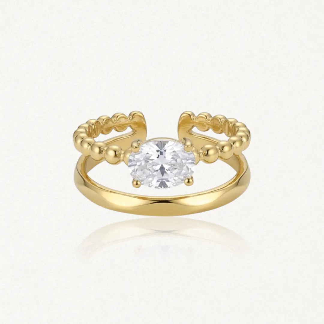 Bague ouverte style diadème en acier inoxydable doré, avec un Zirconium ovale et une bande supérieure perlée de billes.