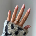 Bague diadème perlée en acier inoxydable doré avec un zirconium ovale sur une main aux ongles roses clairs.