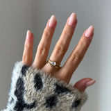 Bague diadème perlée en acier inoxydable doré avec un zirconium ovale sur une main aux ongles roses clairs.