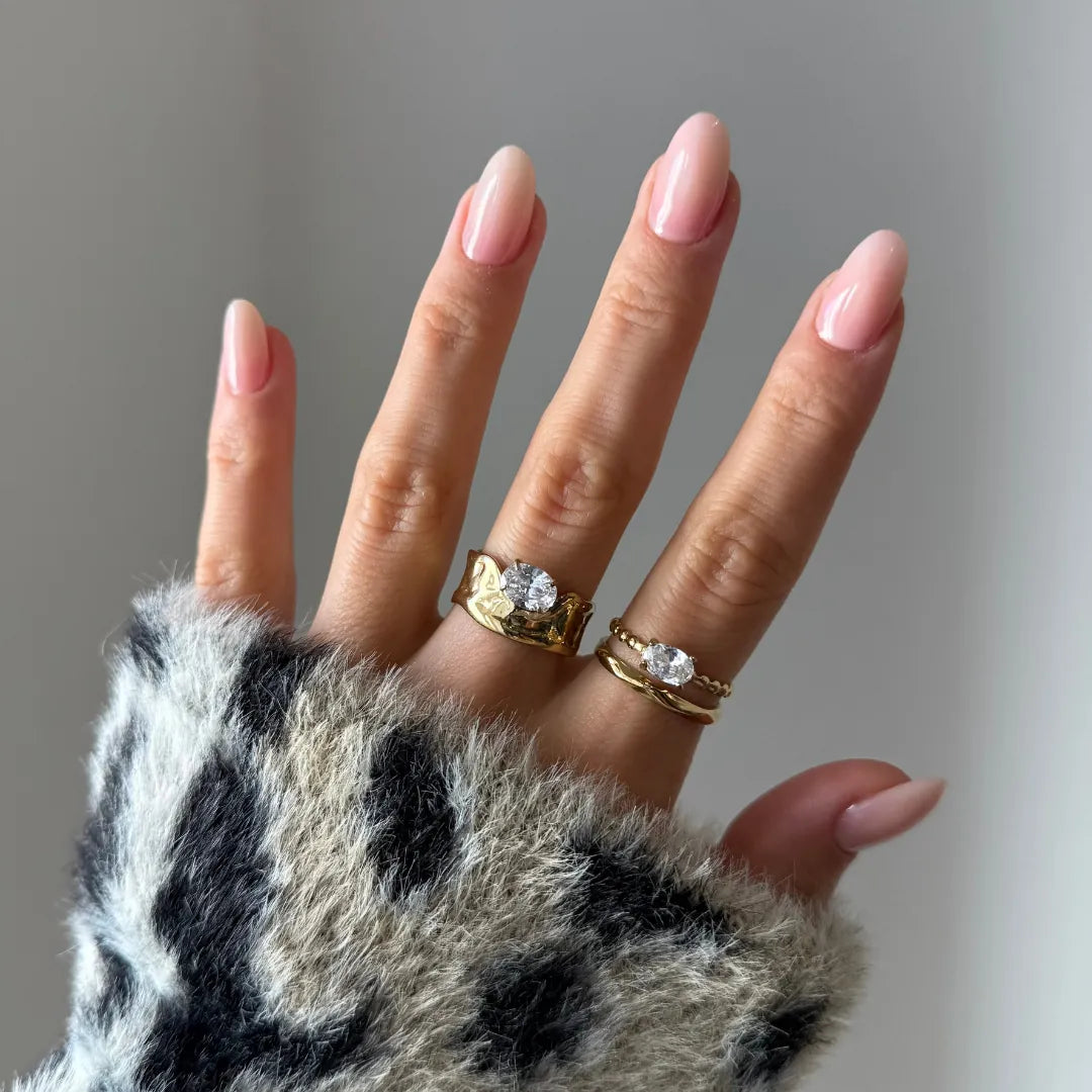 Bague diadème en acier inoxydable doré avec une pierre ovale en zirconium. Une bague fine perlée est aussi visible.