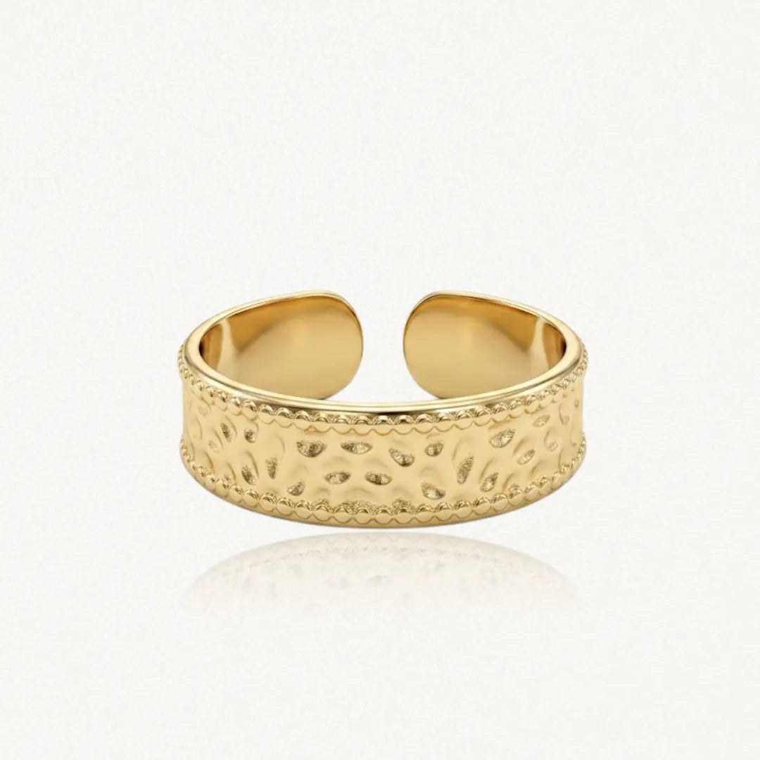 Bague ajustable en acier inoxydable doré, avec un motif martelé et des bordures perlées.