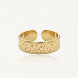 Bague ajustable en acier inoxydable doré, avec un motif martelé et des bordures perlées.