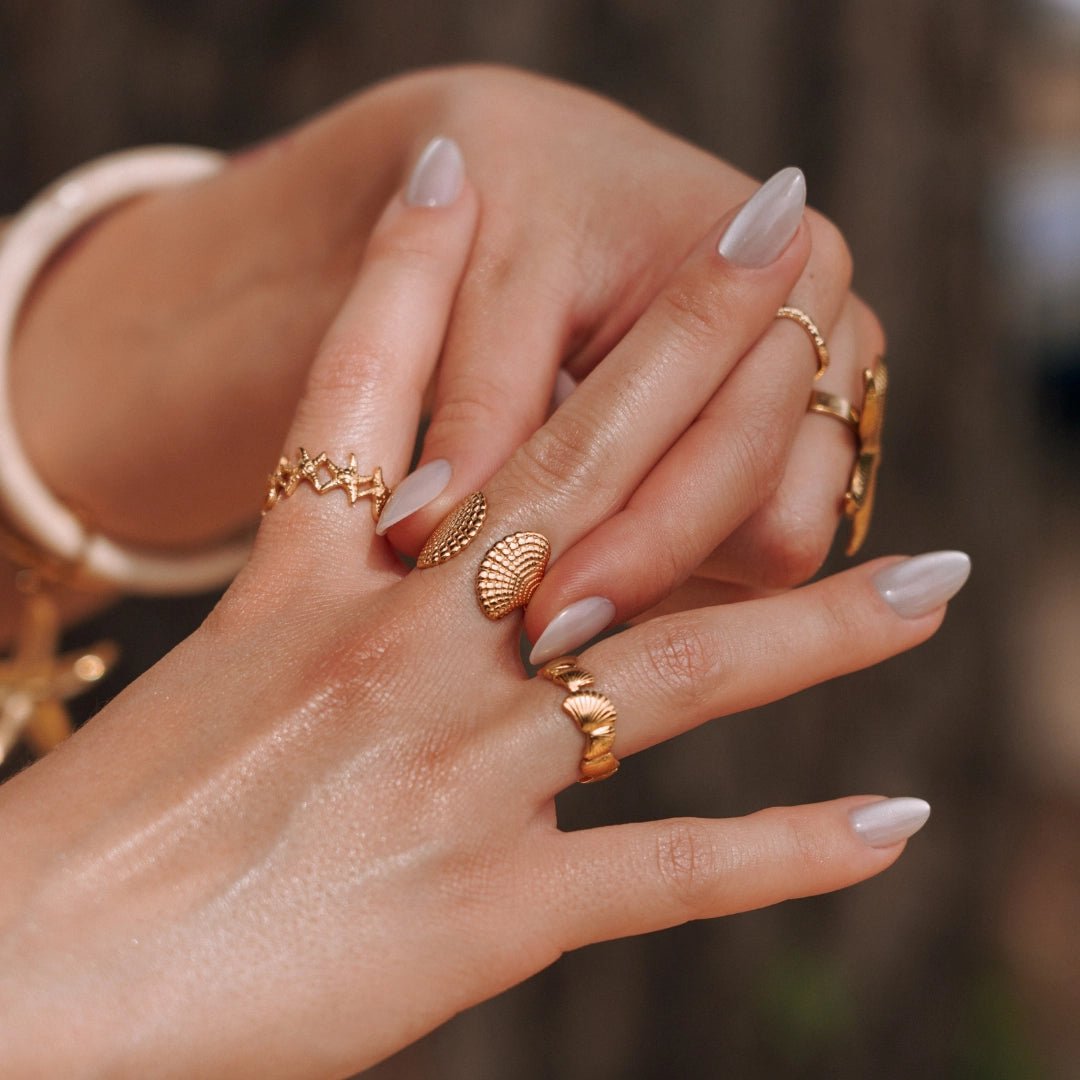 Plusieurs bagues en acier inoxydable doré, dont une bague coquillage et une bague zig-zag.