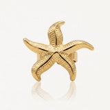 Bague en acier inoxydable dorée, motif étoile de mer texturé et brillant.