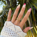 Bague en acier inoxydable doré, motif étoiles et étoile de mer pavée, sur main avec manchette en tricot blanc.