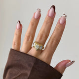 Bague Gigi en acier inoxydable doré avec trois strass en zirconium ovales sertis sur une monture texturée