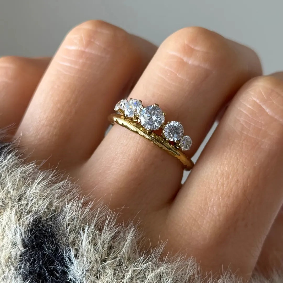 Bague demi-alliance en acier inoxydable doré, le jonc texturé, sertie de cinq zircons ronds de tailles différentes sur un