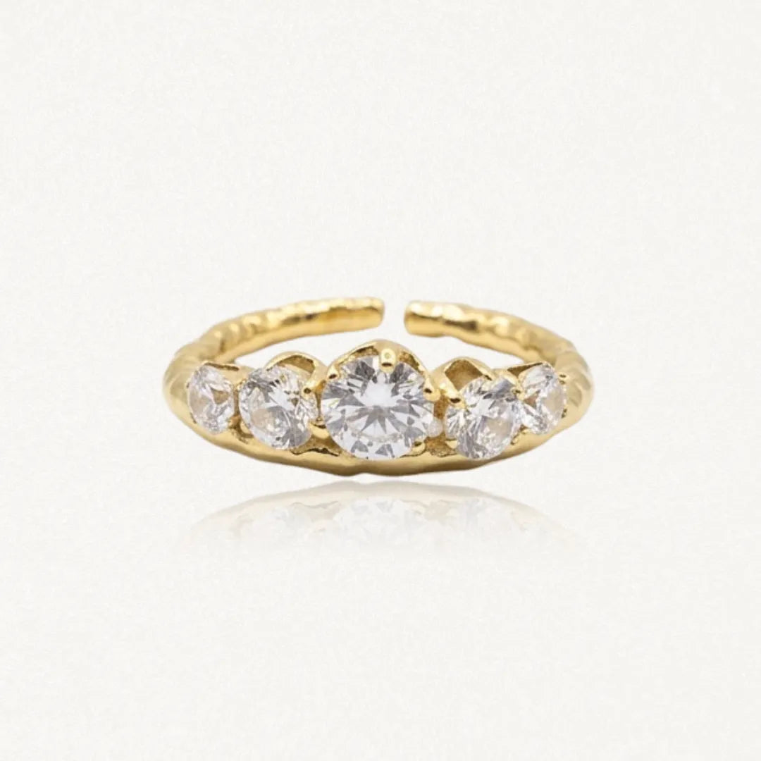 Bague ajustable en acier inoxydable doré, ornée de cinq zircons ronds, le central étant plus grand. Bande texturée.