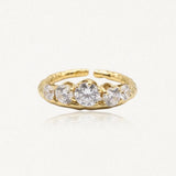 Bague ajustable en acier inoxydable doré, ornée de cinq zircons ronds, le central étant plus grand. Bande texturée.