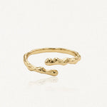 Bague ajustable en acier inoxydable doré, de forme organique irrégulière et texturée.