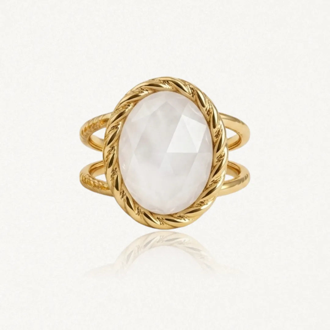 Bague dorée à double corps, ornée d'une pierre ovale blanche facettée dans un serti torsadé.