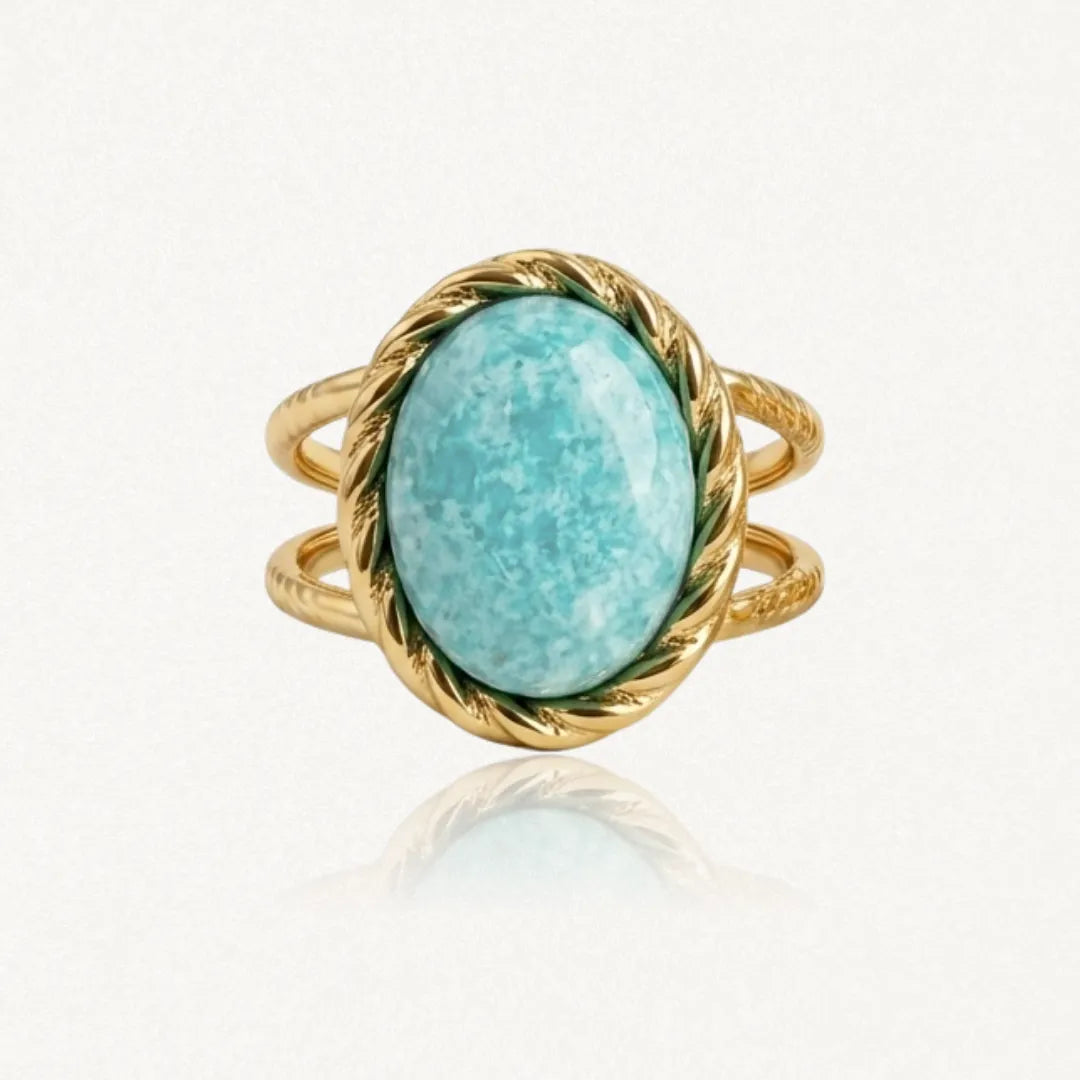 Bague en métal doré, ornée d'une pierre ovale turquoise marbrée de blanc. La monture et l'anneau double sont torsadés.