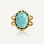 Bague en métal doré, ornée d'une pierre ovale turquoise marbrée de blanc. La monture et l'anneau double sont torsadés.