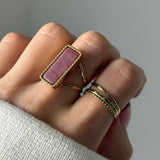 Bague en acier inoxydable doré avec une pierre naturelle rose rectangulaire.