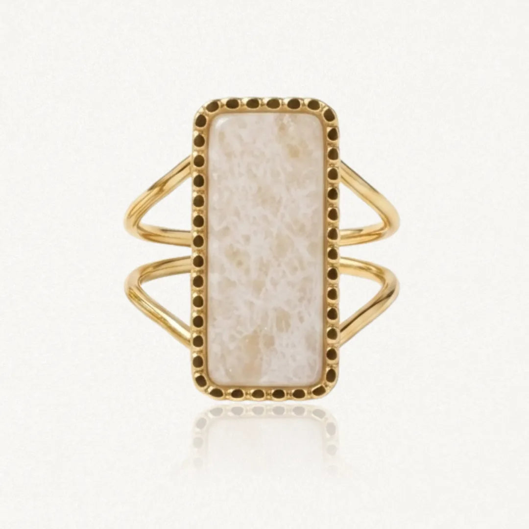 Bague dorée avec une pierre rectangulaire crème veinée, sertie dans un cadre à petits points et un double anneau.