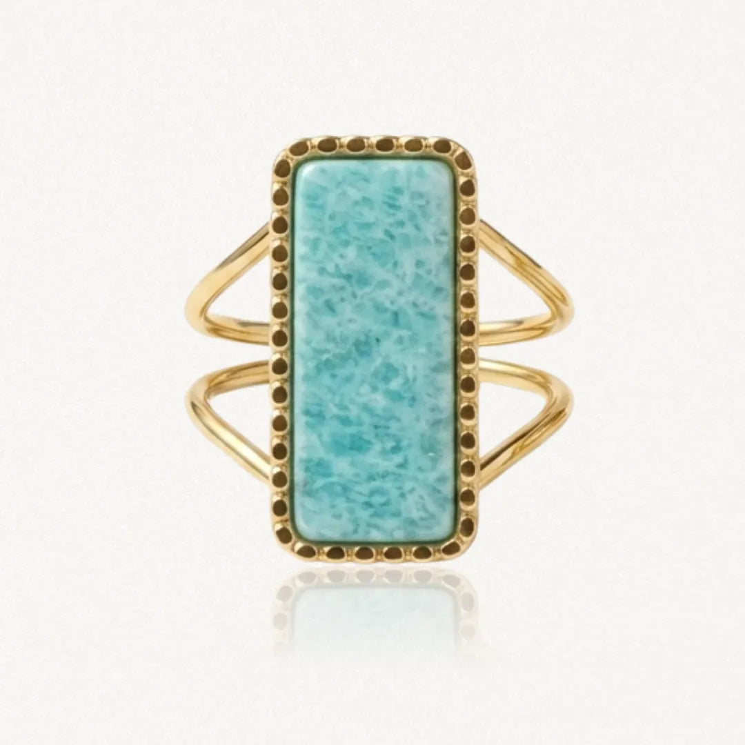 Bague dorée avec pierre rectangulaire bleu-vert veinée, sertie de petits points. Le corps de bague est double.