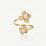 Bague ajustable en acier inoxydable doré, ornée de deux fleurs aux pétales texturés, chacune sertie d'une perle blanche.