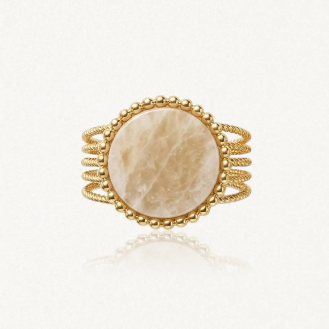 Bague dorée avec cabochon rond marbré beige, bordé de billes dorées et flancs en fils torsadés.