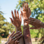 Bagues et bracelets en acier inoxydable dorés aux motifs marins (étoile de mer, coquillage) et soleil sur mains.