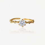 Bague ajustable en acier inoxydable doré avec solitaire central et petites pierres décoratives sur anneau ouvragé.