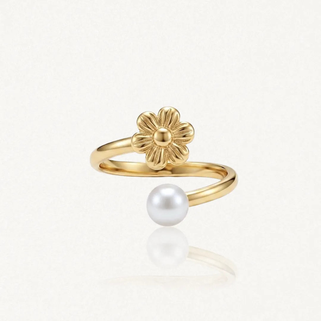 Bague ajustable en acier inoxydable doré, avec une fleur texturée et une perle blanche ronde.