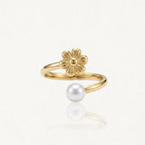 Bague ajustable en acier inoxydable doré, avec une fleur texturée et une perle blanche ronde.