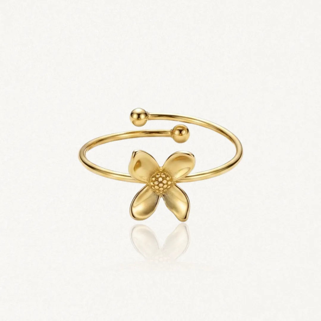 Bague fleur en acier inoxydable doré, avec quatre pétales lisses et un centre pointillé, à anneau ouvert.